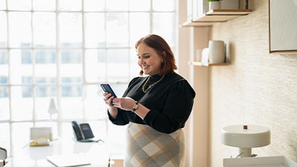 woman looking at her mobile phone in her home office