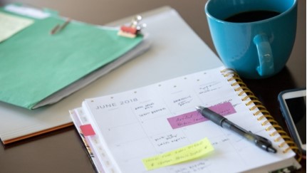 agenda, carpeta y una taza de café sobre un escritorio