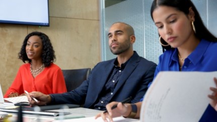 three people sitting at a table in an office