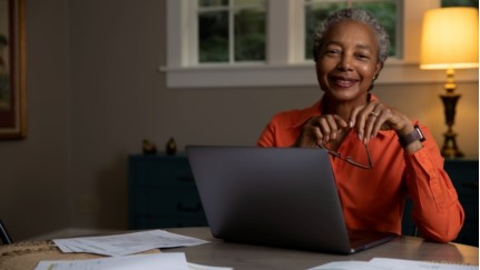 mujer sentada en una mesa con una computadora portátil