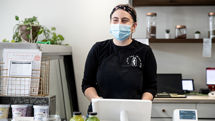 woman wearing a mask working behind a store counter