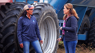 Dos agricultores conversando junto a maquinaria agrícola pesada