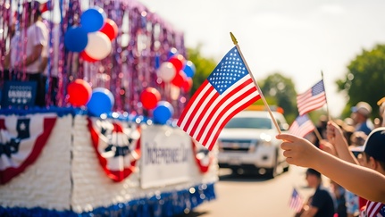 People waving flags and looking at a float at a July 4th parade.