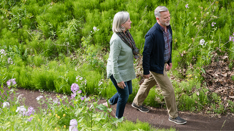  Older smiling couple walking hand-in-hand through woods