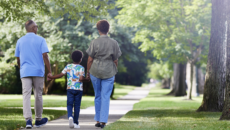  Older smiling couple walking hand-in-hand through woods