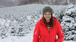 Marji Guyler-Alaniz standing on a tree farm in the snow