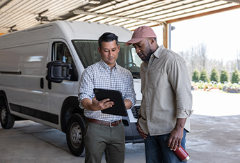 man holding a tablet and standing outside at a landscaping center