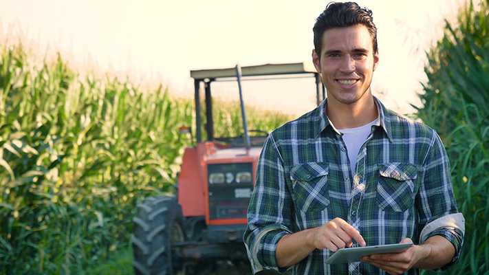 young farmer standing in corn field