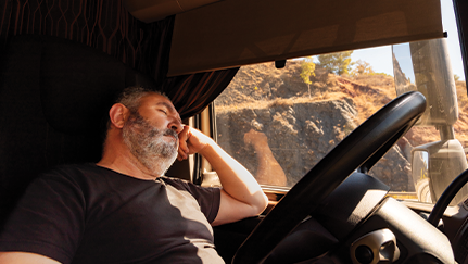 Truck driver resting in the seat of the truck.