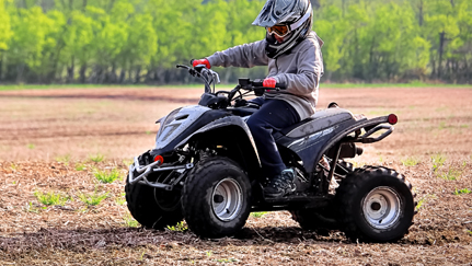 Youth riding ATV with protective helmet