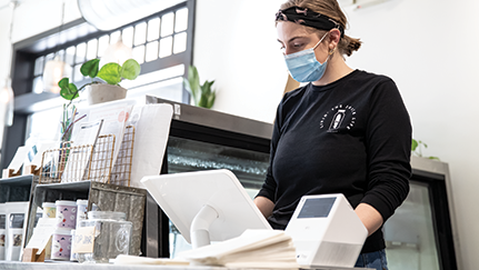 woman wearing a mask working behind a store counter