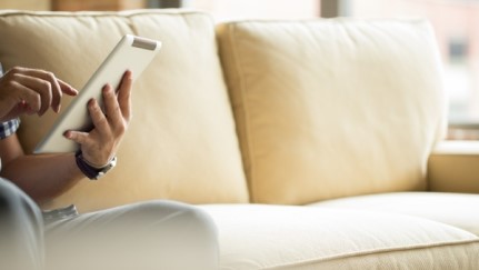 woman sitting on couch using a tablet