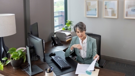 Una mujer que se sienta en su silla de la oficina que mira documentos.
