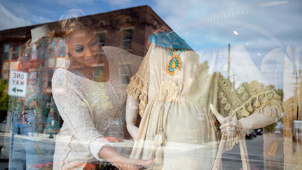woman in a store window adjusting a dress on a mannequin