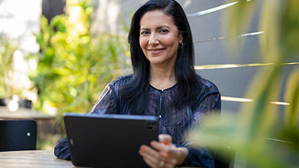 Smiling woman sitting at a table on mobile tablet