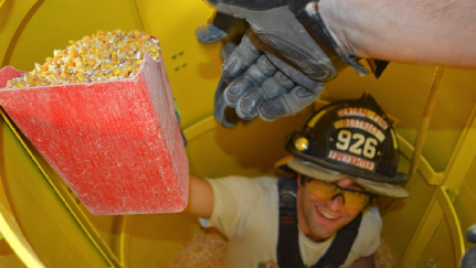 firefighter holding up a scoop of grain