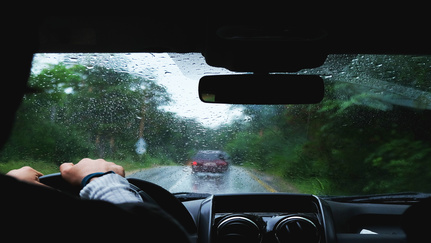 A person drivers their car in the rain.