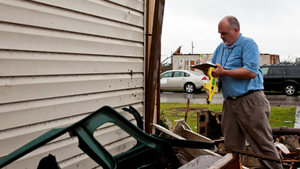 man surveying weather damage outside of a home