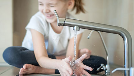 small kid washing hands underneath a faucet