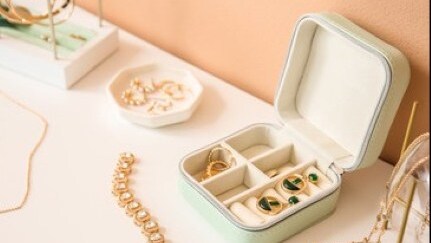 Open jewelry box on table with earrings and rings inside.