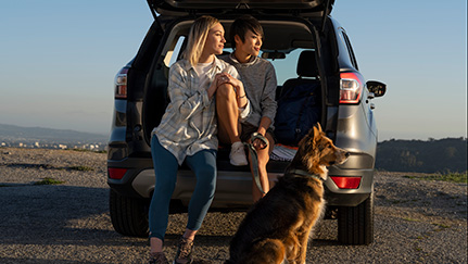 couple and dog at trunk of car looking at sunset