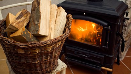 Una canasta de madera frente a una estufa de leña encendida