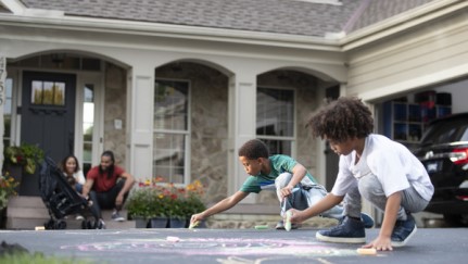 Children drawing with chalk in front driveway of home