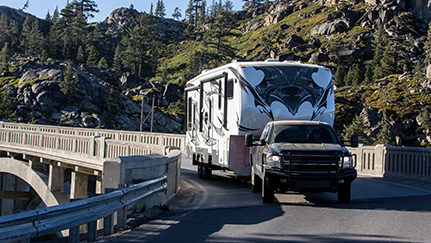 pickup truck towing rv trailer down a curved road