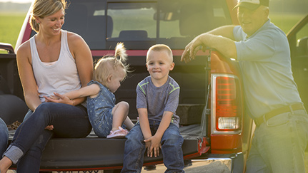 family sitting on the back of a pickup truck