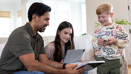Man looking at a tablet with his two children.