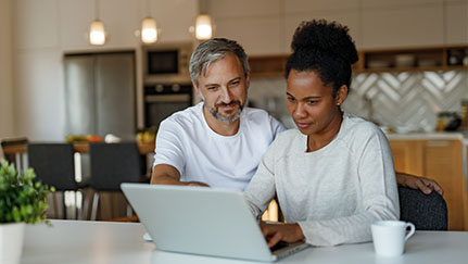 Two people are sitting on a living room couch going over financial documents.