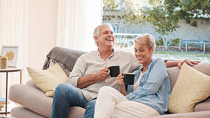 couple holding mugs and sitting on a couch