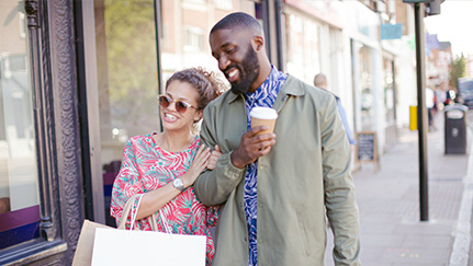 Two individuals walking hand in hand on a city street.