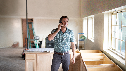 contractor standing in a remodeled house talking on his cell phone