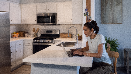 mujer escribiendo en su computadora portátil en su cocina