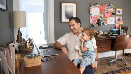 man sitting at desk with daughter sitting on lap