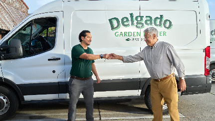two men shaking hands in front of a work van