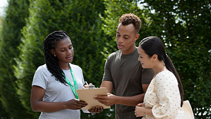 man reviews information on a clipboard with two women