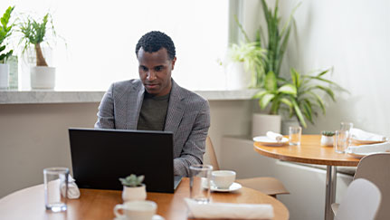 man typing on laptop in cafe