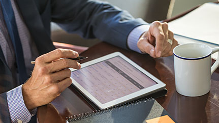 man reviewing investments on a tablet in his office