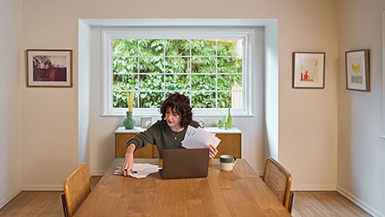 woman reviewing bills while sitting at her dining room table