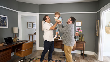 two guys playing with a toddler in the living room