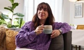 Woman relaxing on a couch, smiling and holding a mug