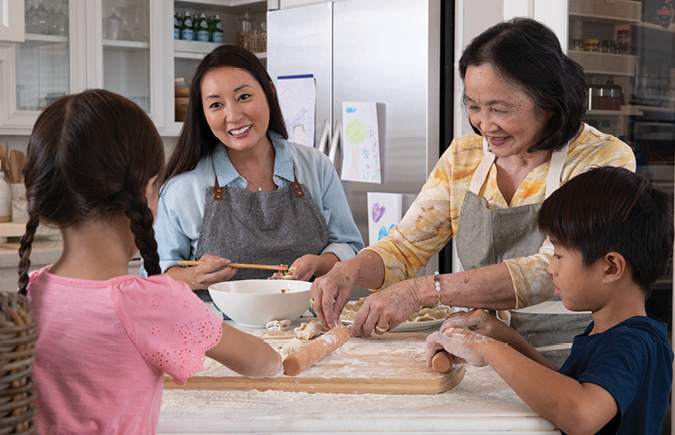 A retired woman bakes with her daughter and grandchildren.