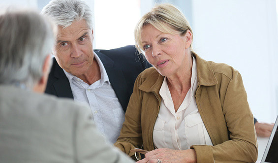 Man and woman couple sitting at a desk and talking with their financial professional.