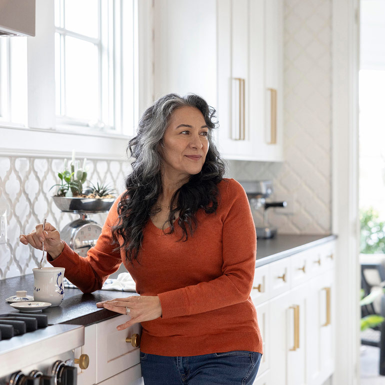 A retired woman makes tea in her kitchen.