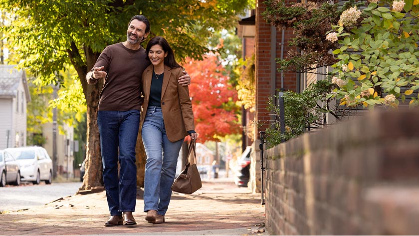 A married couple smiles while walking through their neighborhood together.