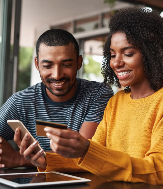 Man and woman sitting down looking at a phone and smiling.