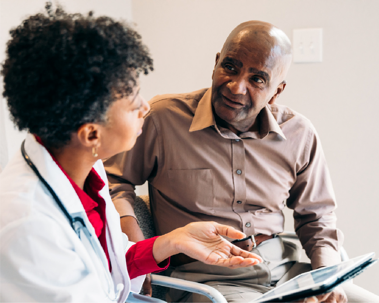 Woman doctor sitting down and looking at a table with a male patient.