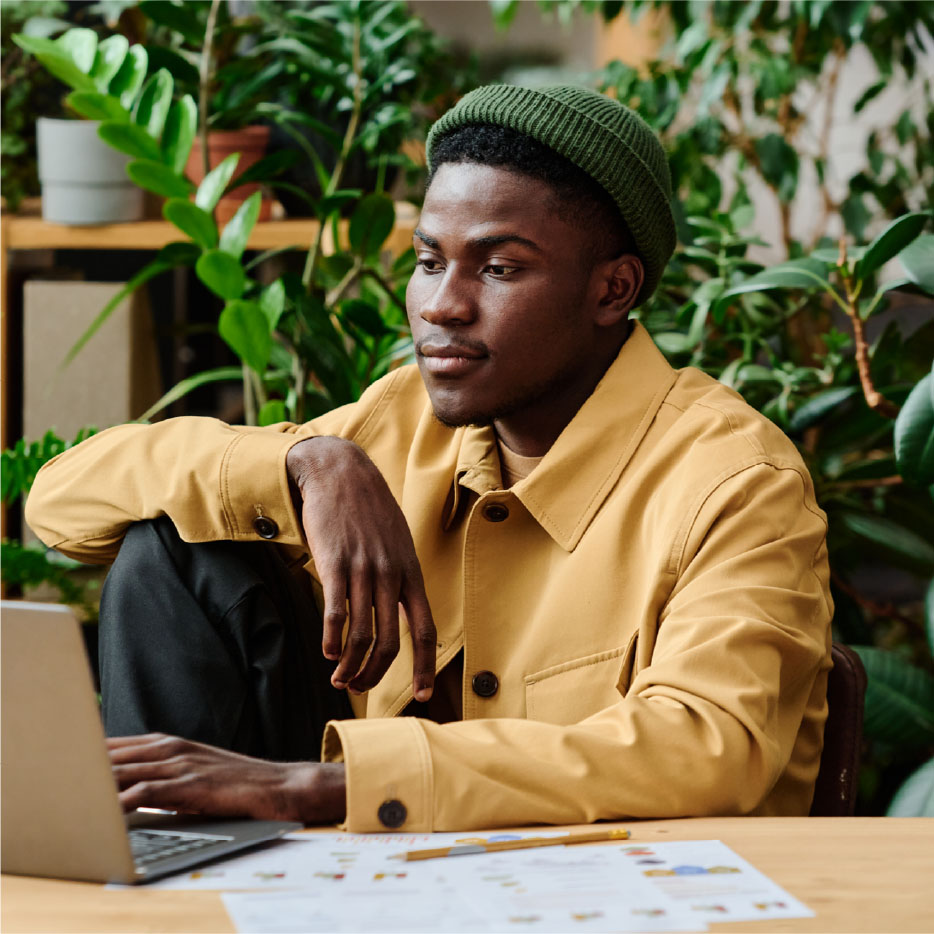 Gen Z man sitting at a desk looking at a laptop